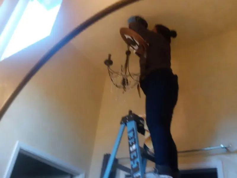 Electrician installing a chandelier in a Adel residence